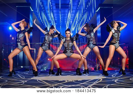 Group of sexy stunning young girls dancing together at the nightclub on stage entertainment leisure disco celebration festive show showgirls ballet diverse outfits stage costumes go-go concept.