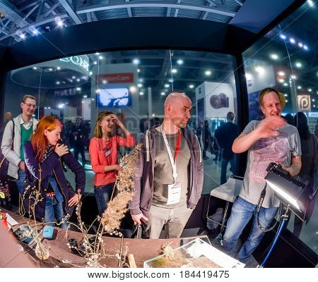 MOSCOW RUSSIA - APRIL 21 2017: Attendees of macro photography workshop at booth of Olympus company at PhotoForum 2017 put millipede for fun on bald spot in Moscow Russia on April 21 2017.