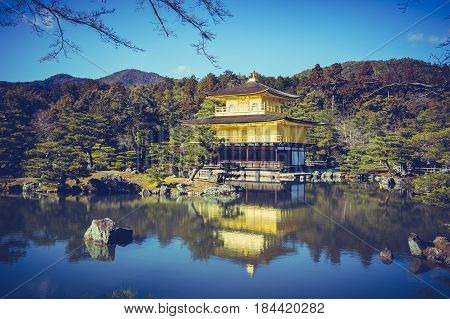 Beautiful Architecture of Kinkakuji Temple (The Golden Pavilion) reflected on surface of water. Tourism of Japan Kyoto during autumn season. Outdoor with blue sky and green trees. Vacation background