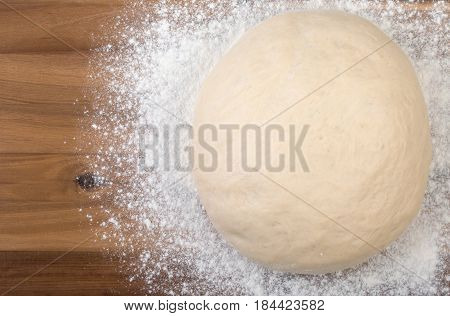 Ball A Dough And White Flour On A Wooden Cutting Board. Top View, Close Up.