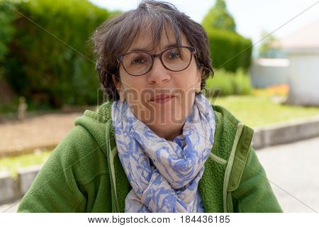 Portrait of a mature brunette woman with eyeglasses in garden