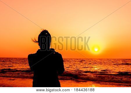 Silhouette the women shooting image with smartphone on sand beach landscape nature with color of sunset in twilight dark style