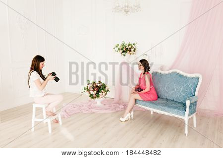 Young sexy photographer is taking pictures the model in the studio