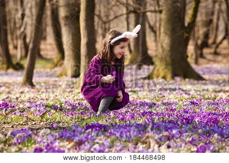 Little girl with banny ears peeping from behind a tree in the park