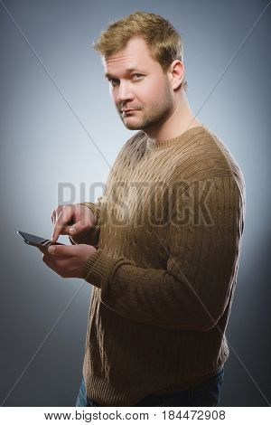 Close-up portrait of a angry young man talking on cell phone isolated on gray background.