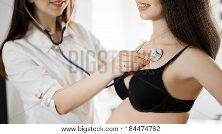 Female Medicine Doctor Holding Stethoscope To Pregnant Woman Standing For Encouragement, Empathy, Ch