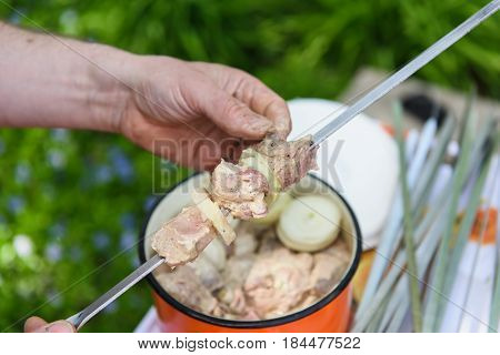 Man stringing meat on a skewer. Shashlik - cooking barbecue. Stringing meat on ramrod.