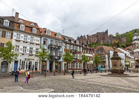 HEIDELBERG GERMANY - MAY 3 2013: People walking on Kornmarkt square in Heidelberg old town Germany. Madonna statue on foreground and Heidelberg castle on the background
