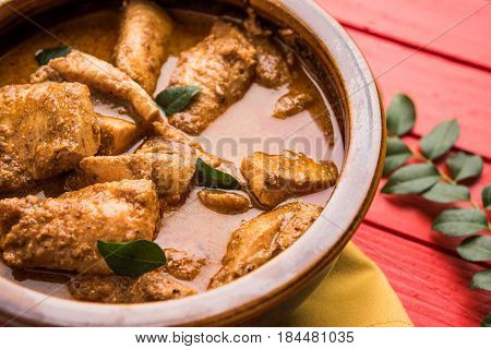 tasty fish curry served with white cooked basmati rice with curry leaves in the background, favourite coastal indian food
