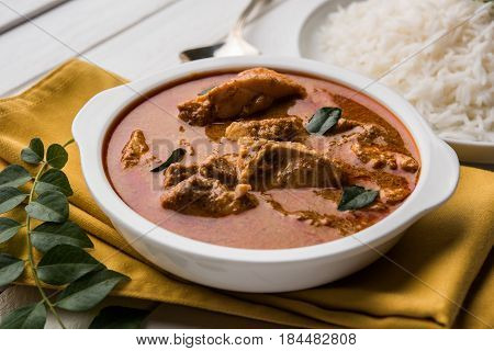 tasty fish curry served with white cooked basmati rice with curry leaves in the background, favourite coastal indian food