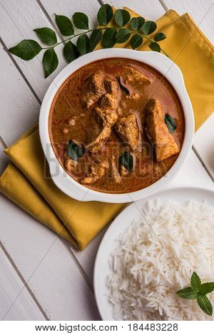 tasty fish curry served with white cooked basmati rice with curry leaves in the background, favourite coastal indian food