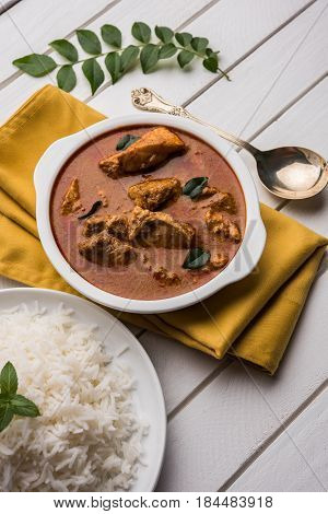 tasty fish curry served with white cooked basmati rice with curry leaves in the background, favourite coastal indian food