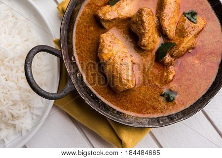 tasty fish curry served with white cooked basmati rice with curry leaves in the background, favourite coastal indian food