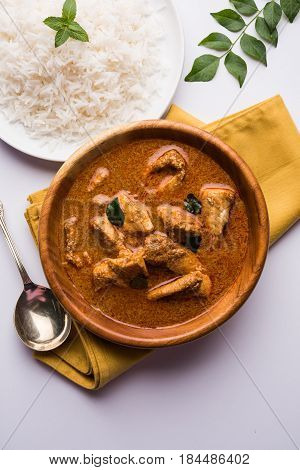 tasty fish curry served with white cooked basmati rice with curry leaves in the background, favourite coastal indian food