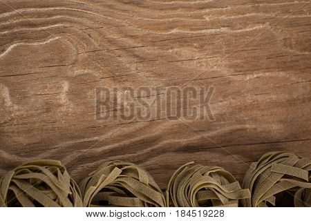 Tagliatelle pasta arranged in a row on wooden background