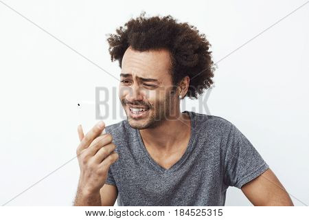 Young cheerful african man smiling looking at phone over white background.