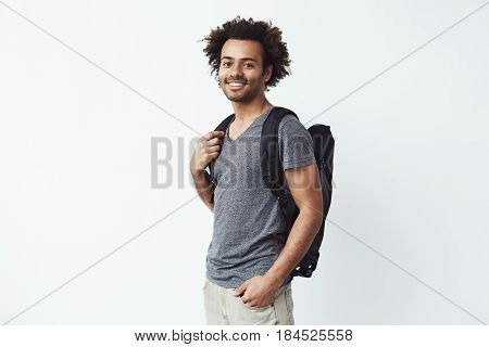 Cheerful african man with backpack smiling looking at camera. White background. Copy space.