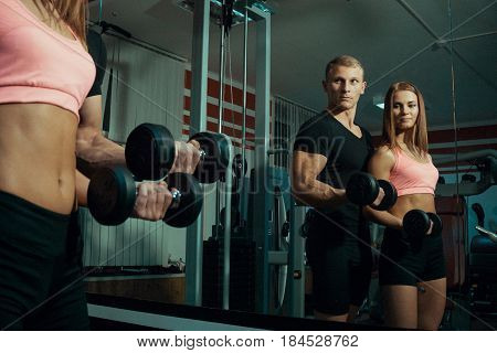 Man and woman doing exercise with dumbbells in the gym.