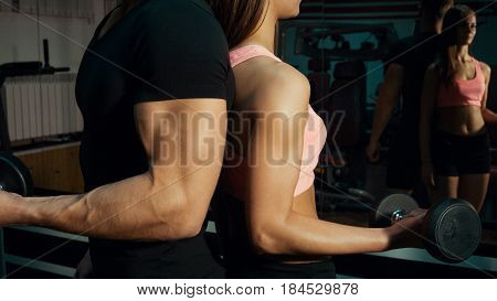 Man and woman with dumbbells in the gym.