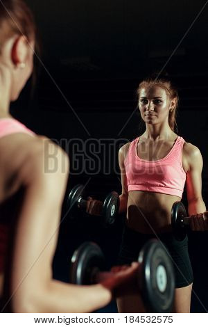 Young woman with a dumbbell in the gym.