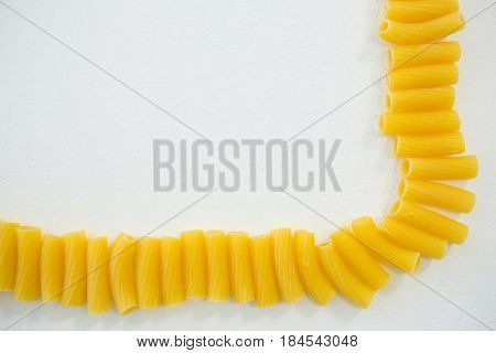 Sedani rigati pasta on arranged in a row on white background