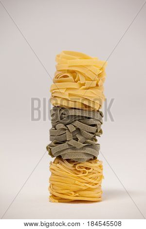 Roll of tagliatelle pasta on white background