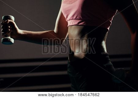 Beautiful body of a young woman with dumbbells in his hands.