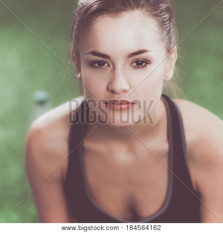 Beautiful young woman relaxing after exerscises on the grass 