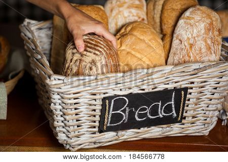 Hand of female staff holding breads at counter in bakery shop