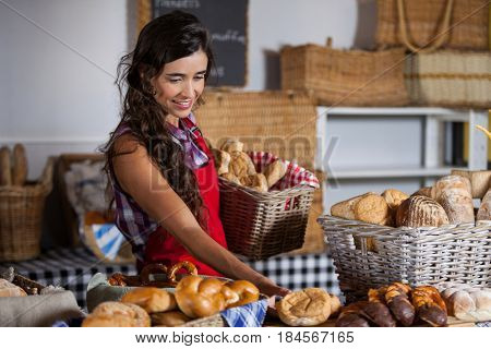 Female staff holding basket of sweet foods in bakery section of supermarket