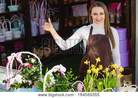 Positive flower shop owner looking at camera and showing thumbs up. Small business owner