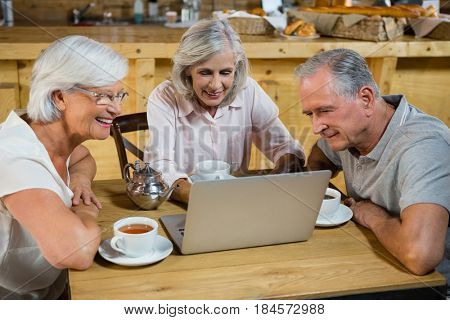 Group of senior friends using laptop in cafÃÂ©