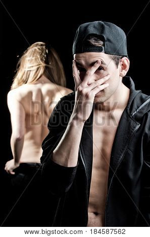 naked sexy girl showing graceful back and young shy guy man in black cap and shirt has bare torso holds hand on face seduction and relations spying and confusion sex education and services