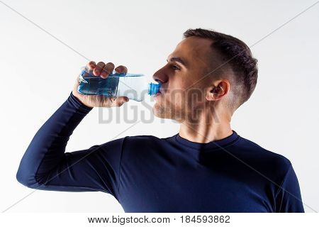 A man with a bottle of water. Sportsman with a bottle of water. Side view.