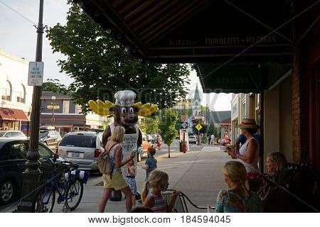 HARBOR SPRINGS, MICHIGAN / UNITED STATES - AUGUST 4, 2016: An entertainer in a moose costume greets visitors outside Kilwin's Candy Store, during the Street Musique event on Main Street in downtown Harbor Springs.