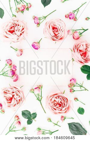 Floral frame made of pink roses, buds and leaves on white background. Flat lay, top view. Floral pattern.