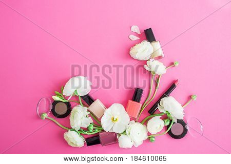 Feminine desk with woman cosmetics, white flowers and petals on pink background. Flat lay, top view. Beauty background