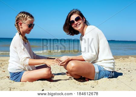 Daughter and her mom playing with sand on the beach