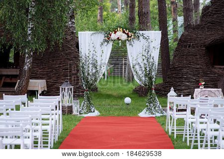 Beautiful Wedding Ceremony Outdoors. Decorated Chairs Stand On The Grass. Wedding Arch Made  Flowers
