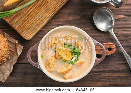 Delicious beer cheese soup with croutons and onions on table