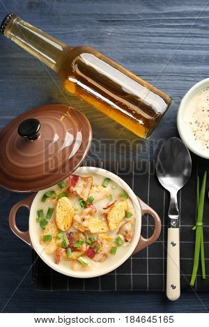 Delicious beer cheese soup with croutons and fried bacon on table