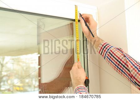 Male hands marking off window frame