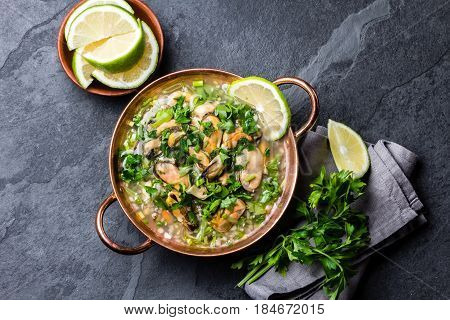 Latin American ceviche o mariscal - raw seafood cold soup wish mussels, clams, prawns, lime, onion in copper bowl on slate background. Seafood shellfish ceviche. Traditional dish of Peru or Chile