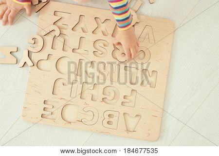 Hands of cute little child playing with letters at home