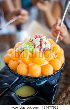 bingsu is a Korean shaved ice dessert with sweet toppings such as chopped fruit, condensed milk, fruit syrup, and red beans.