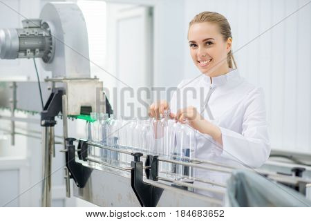 Female worker placing empty bottles on the line at a water factory