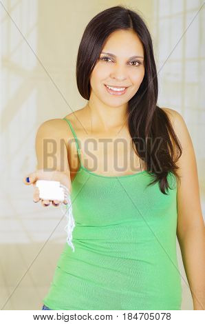 Young beautiful woman with a green blouse holding a hygenic towel with one hand and pointing in front of herself.