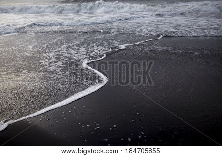 Black sand beach on the sunrise with white Indian ocean. Nobody in the beach. Paradise