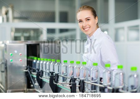 Female worker near conveyour at a water factory