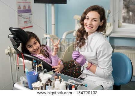 Smiling Female Dentist And Girl Patient After Treating Teeth At Dental Clinic Office, Looking To The